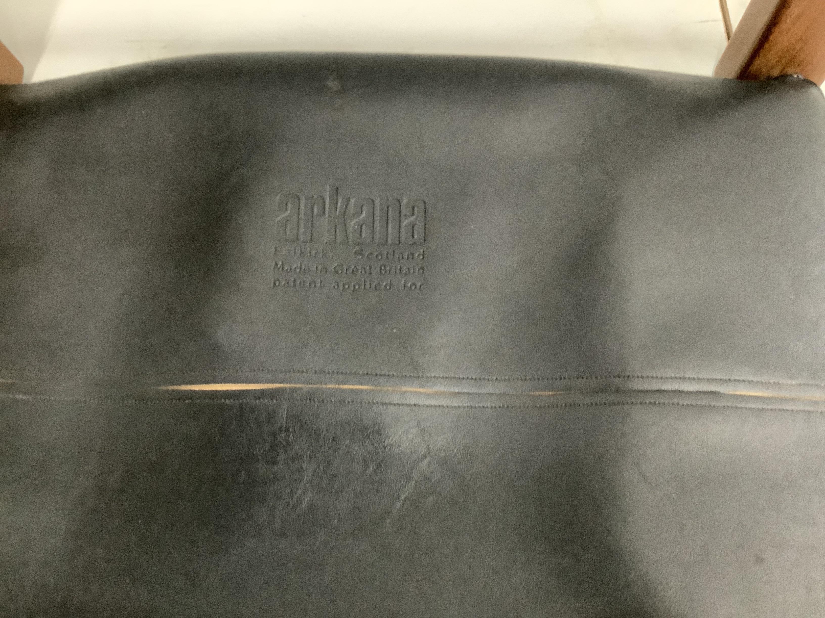 Maurice Burke for Arkana, a black leather and teak safari armchair, width 62cm, depth 60cm, height 72cm and foot stool